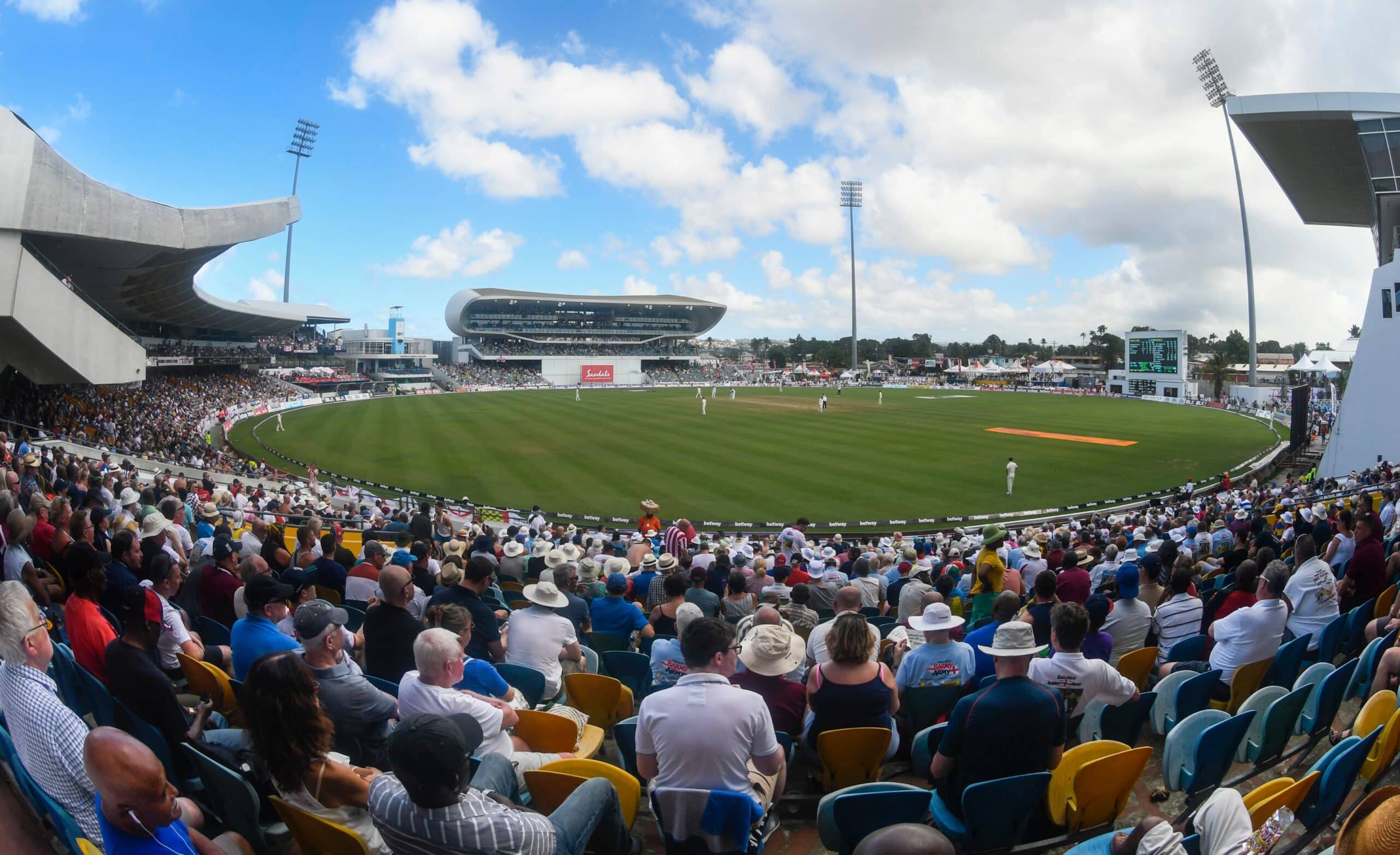 Wide view of cricket pitch with fans